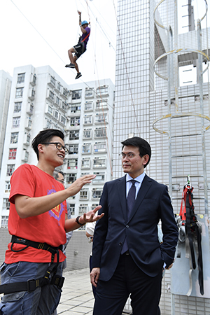 The Secretary for Commerce and Economic Development, Mr Edward Yau, today (June 14) visits the headquarters of Youth Outreach in Sai Wan Ho during his visit to Eastern District. Photo shows Mr Yau (first right) touring a rope course set up at the rooftop of the building.